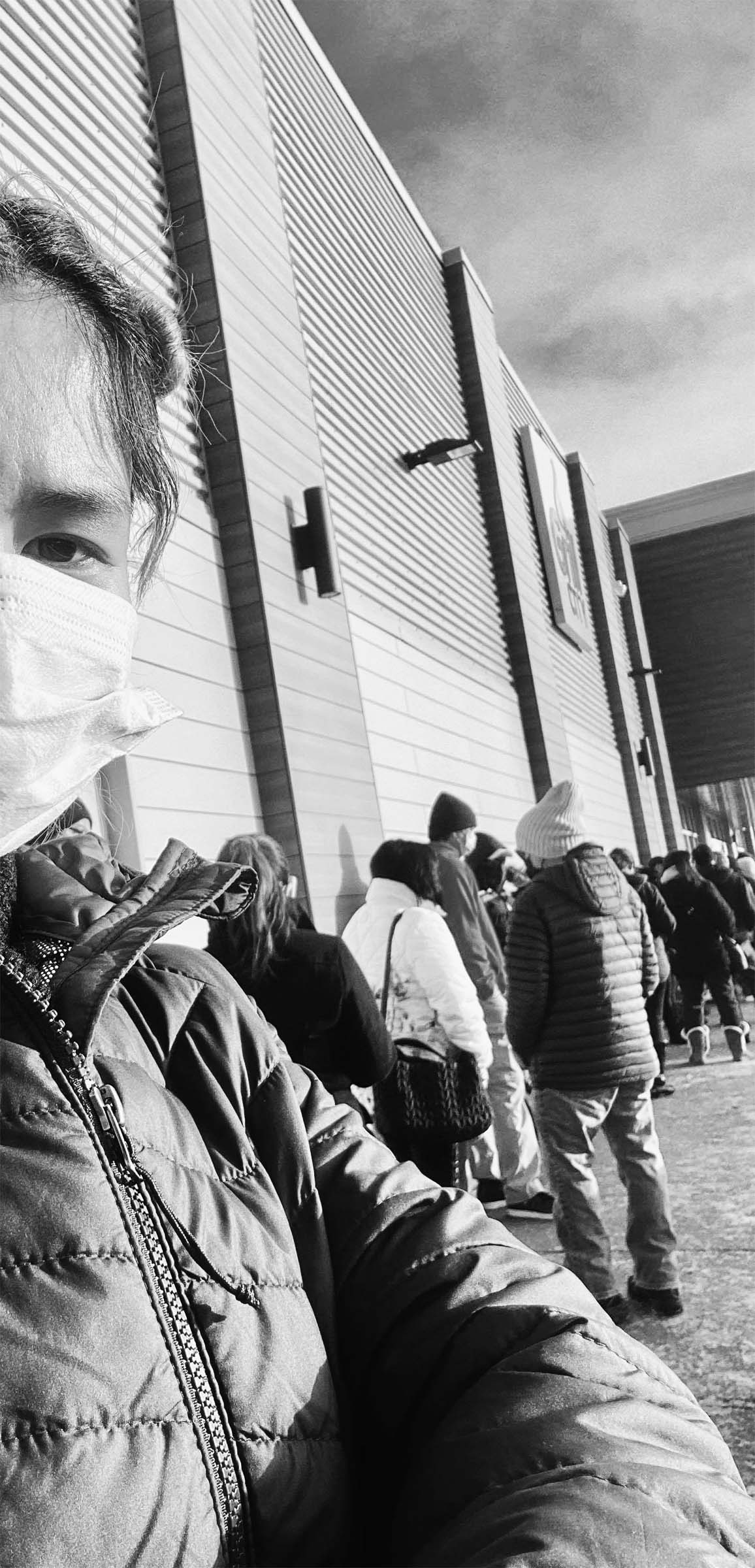 Women in line staring at the camera wearing a mask